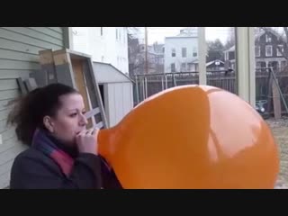 orange balloon blown really big till it pops in the rain